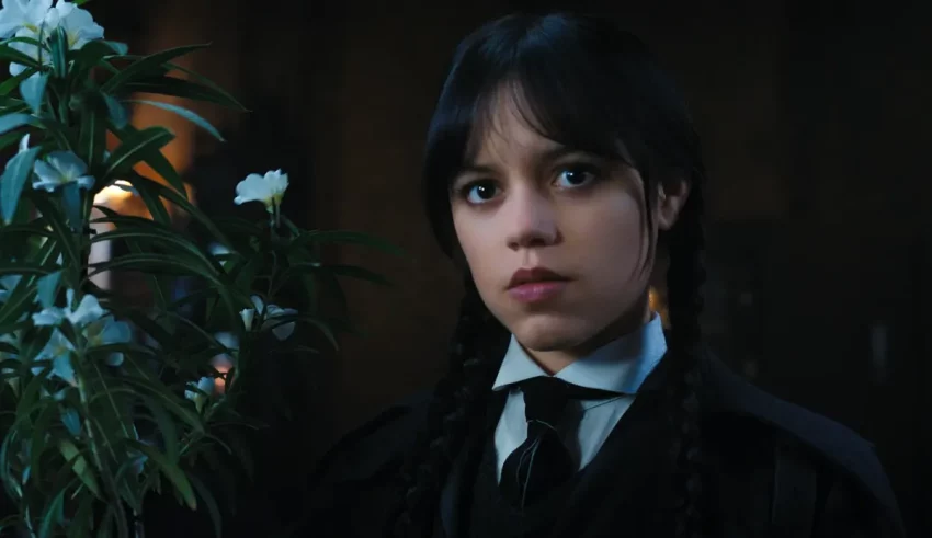 A young girl in a black suit holding a flower.