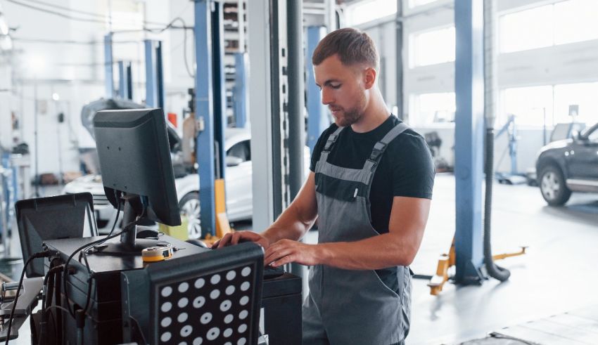 A mechanic working on a computer in a garage.