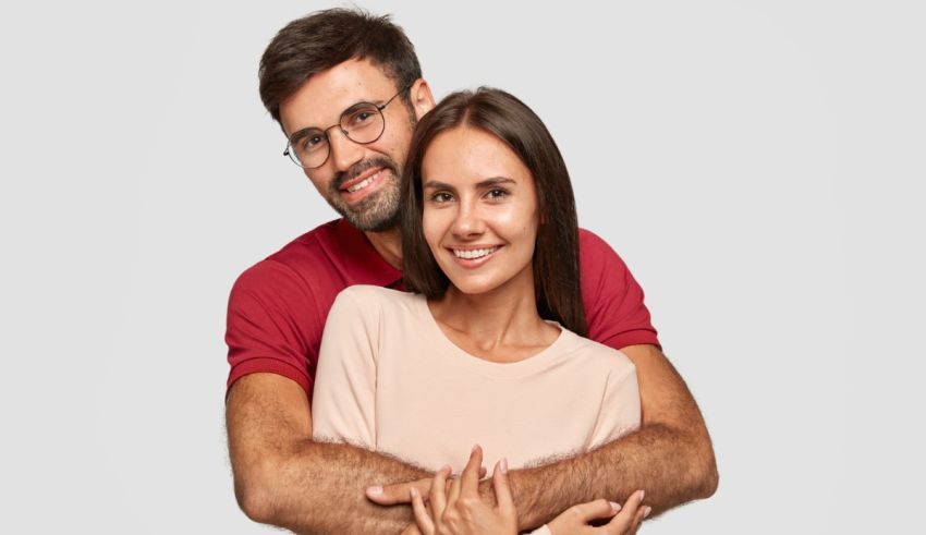 A man and woman hugging each other on a gray background.