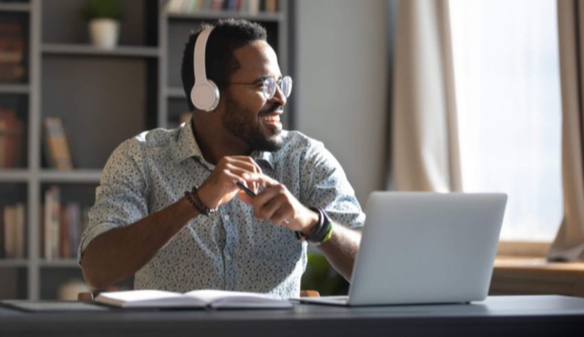 A man wearing headphones is sitting at a desk with a laptop.
