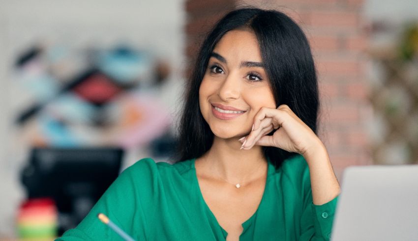 A young woman sitting at a desk with a laptop.