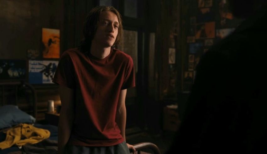 A young man in a red shirt is standing in a room.