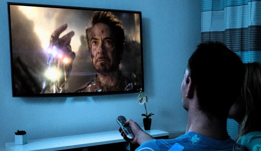 A man and woman watching a movie on a tv.