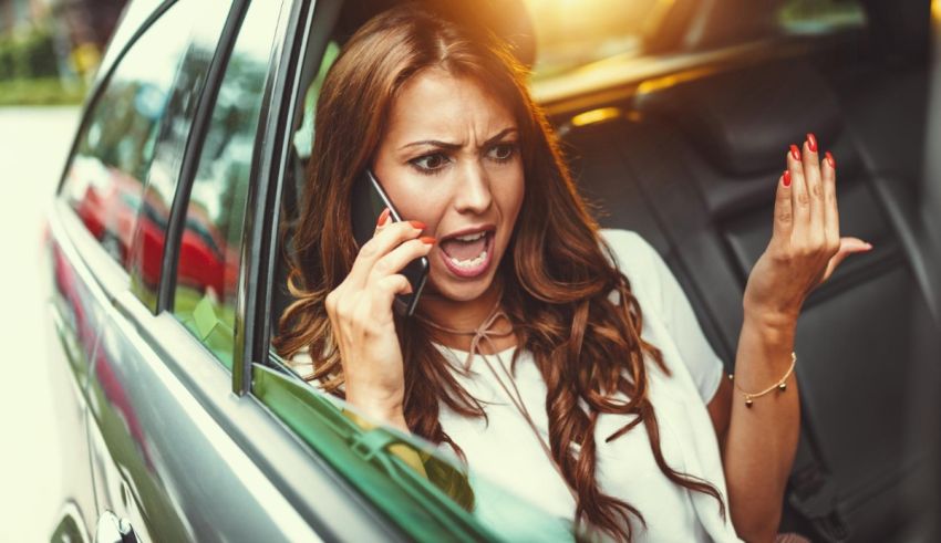 A woman talking on the phone while sitting in the back seat of a car.