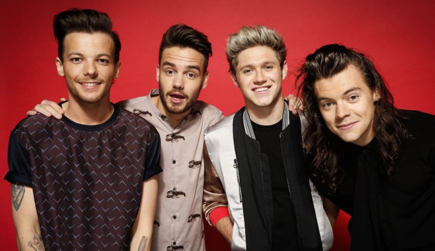One direction pose for a photo in front of a red background.