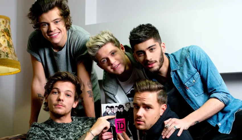 One direction is posing for a picture with a book.