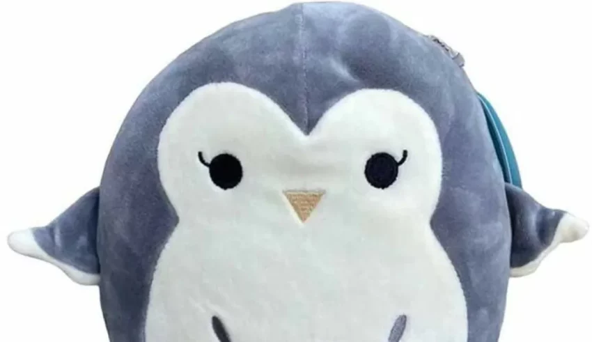 A stuffed penguin sitting on a white surface.