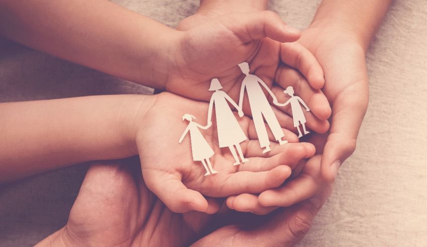 The hands of a family holding a paper cut out of a family.
