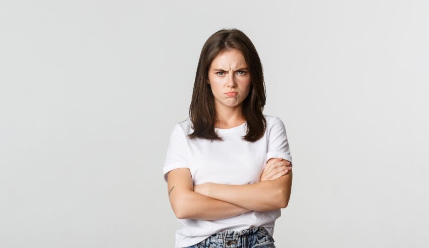 A young woman in a white t - shirt with her arms crossed.