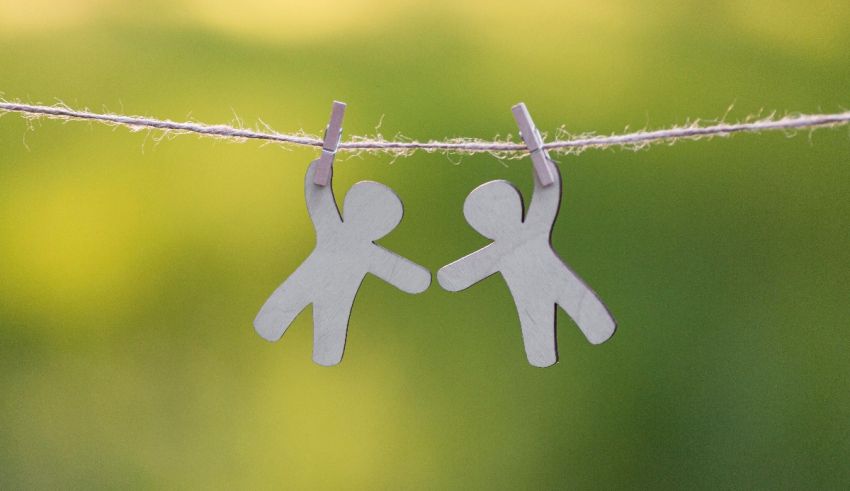 A pair of silver earrings hanging on a string with a green background.