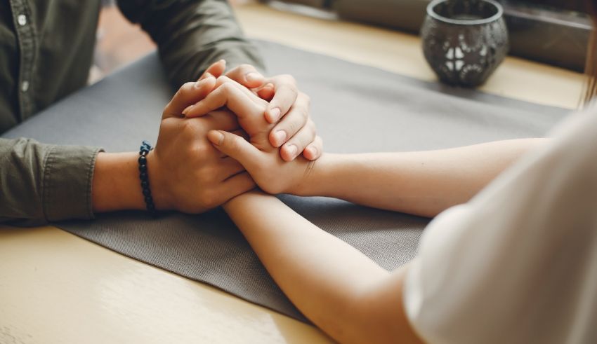 A man and woman holding hands on a table.