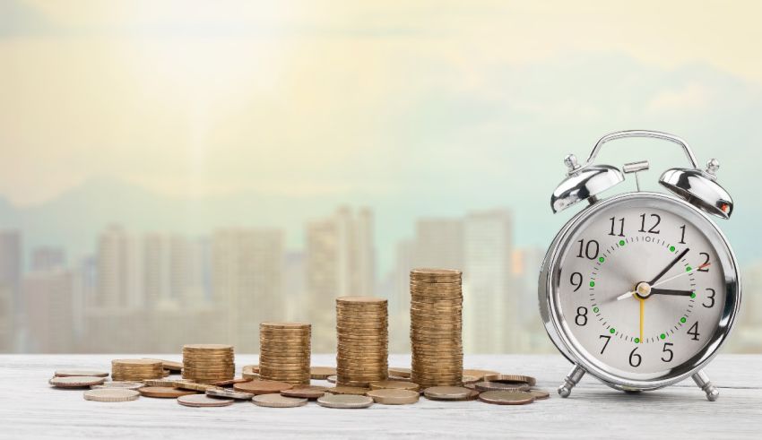 An alarm clock and coins on a table in front of a city.