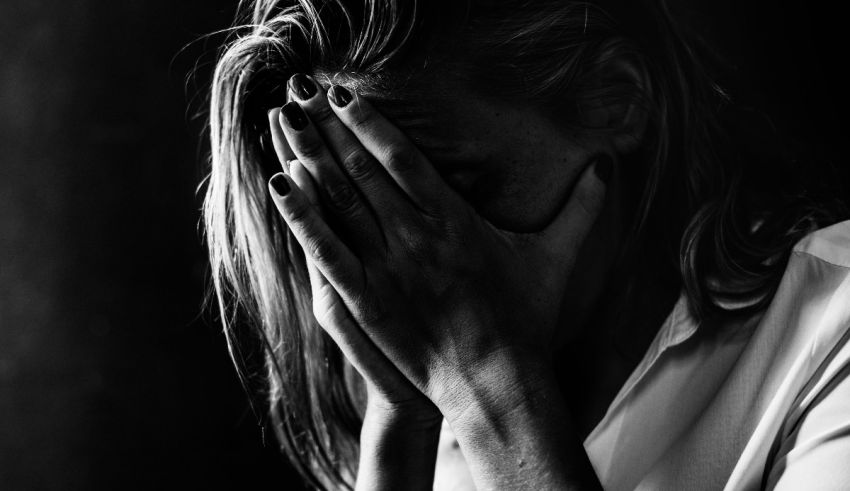 A black and white photo of a woman covering her face.
