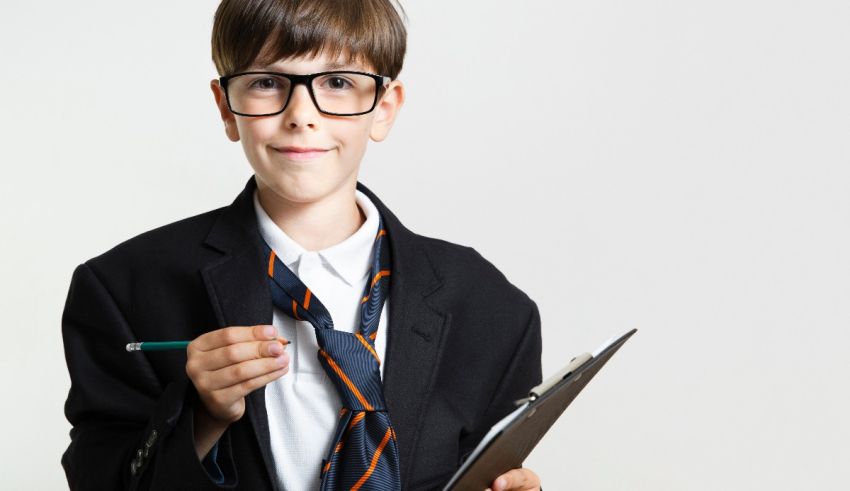 A young boy in a suit and tie holding a clipboard.