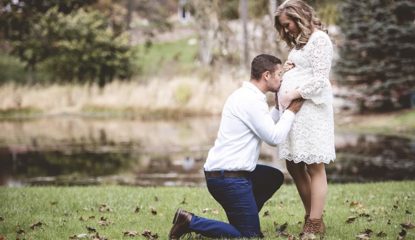 A pregnant woman kneeling in front of a pond.