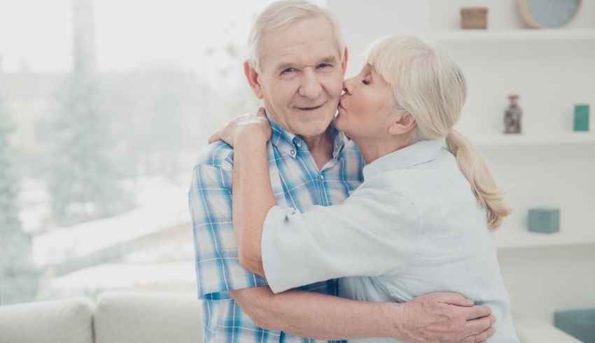 An older couple hugging each other in a living room.