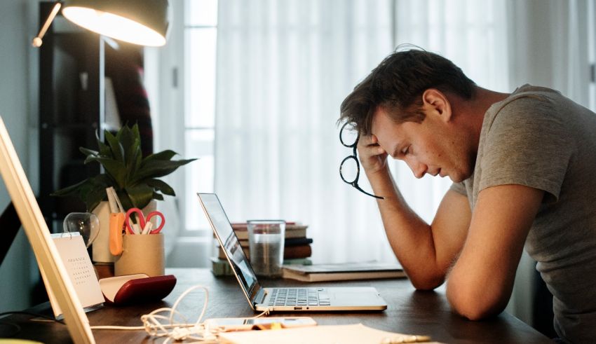 A man is sitting at a desk with a laptop in front of him.