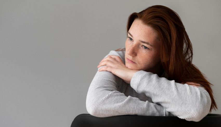 A young woman leaning on a chair with her arms crossed.