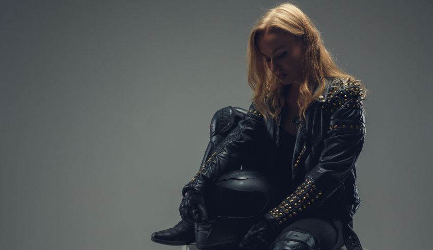 A woman in a leather jacket sitting on a motorcycle.