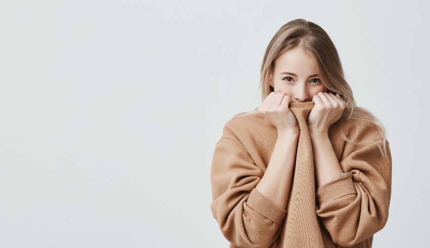 A young woman covering her face with a sweater.
