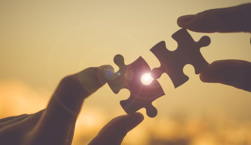 Two hands holding a piece of jigsaw puzzle.