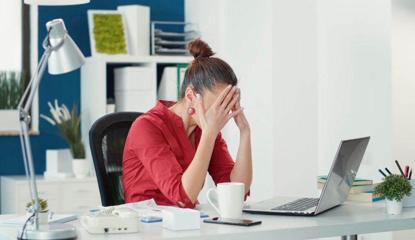 A woman is sitting at a desk with a laptop in front of her.