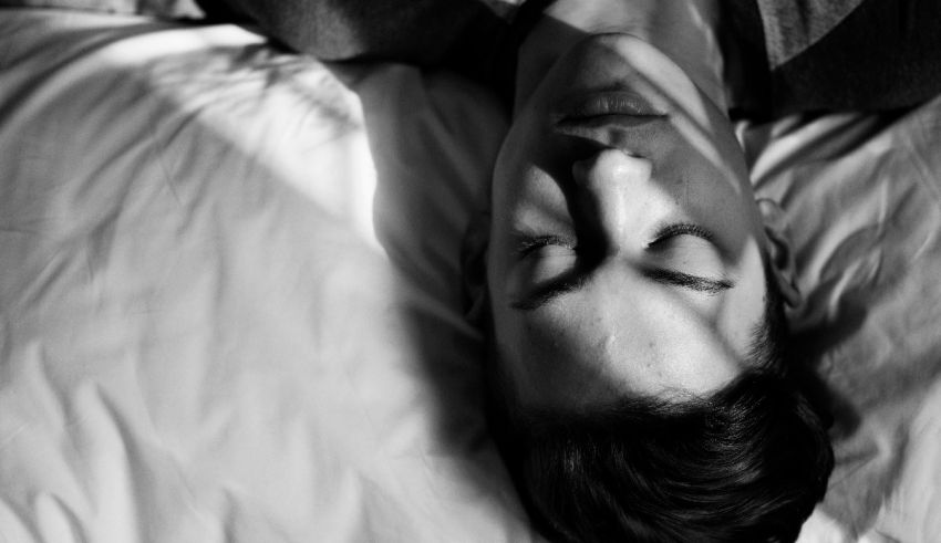 A black and white photo of a man laying on a bed.