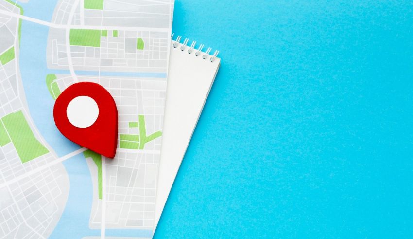 A map with a red pin on it and a notebook on a blue background.