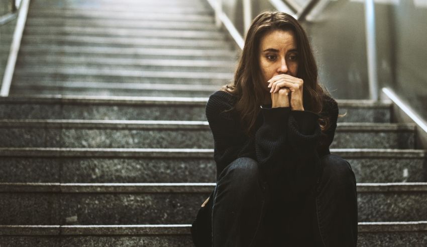 A woman sitting on the stairs with her hand on her face.