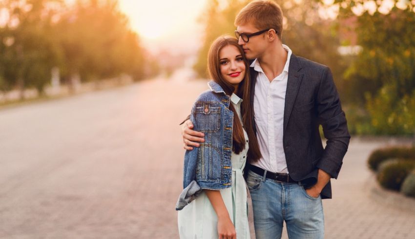 A young man and woman hugging in the street at sunset.