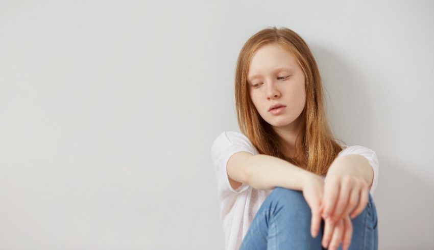 A young girl sitting on the floor with her hands on her knees.