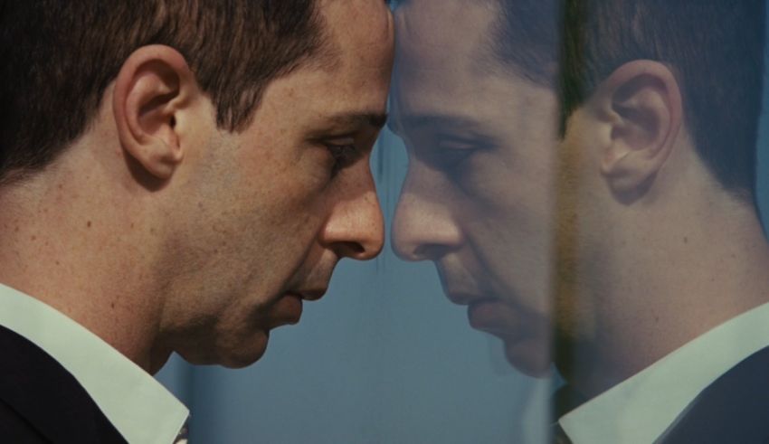 A man in a suit and tie looking at his reflection in a mirror.