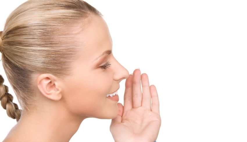 A woman is holding her hand up to her ear.