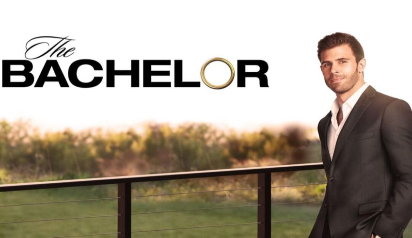 A man in a suit is standing in front of a fence.