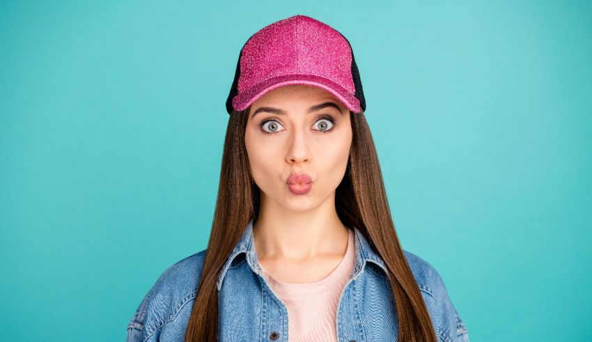 A young woman wearing a pink baseball cap and making a funny face.