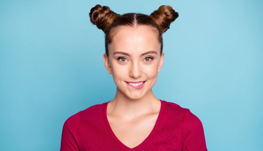 A young woman with buns in her hair on a blue background.