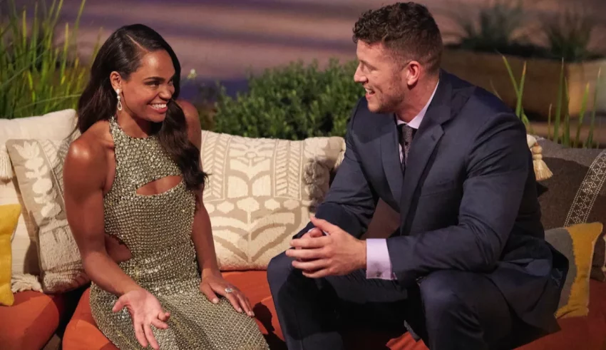 A man and woman sitting on an orange couch.
