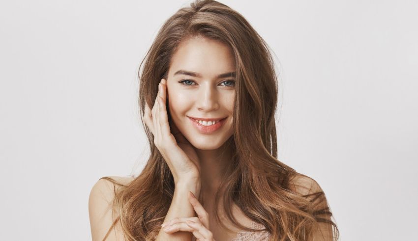 A young woman posing with her hands on her face.