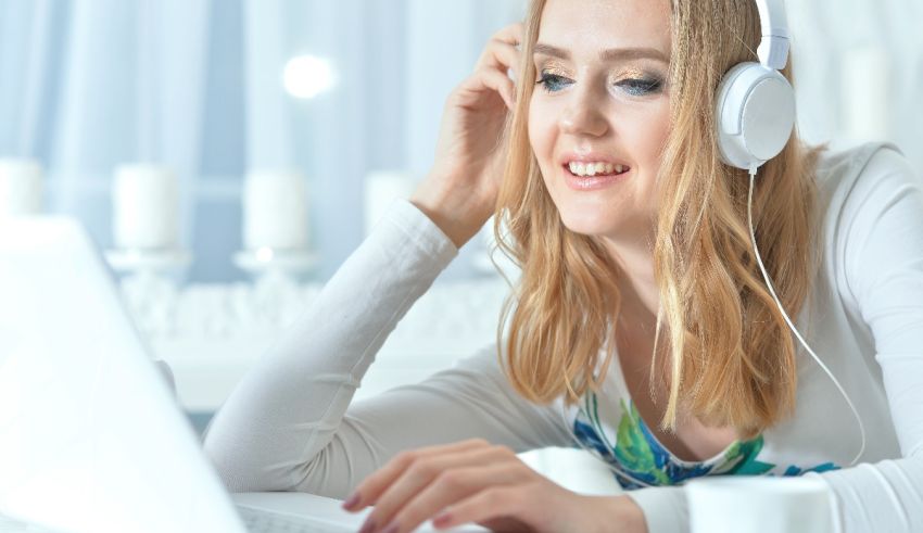 A young woman is listening to music on her laptop.