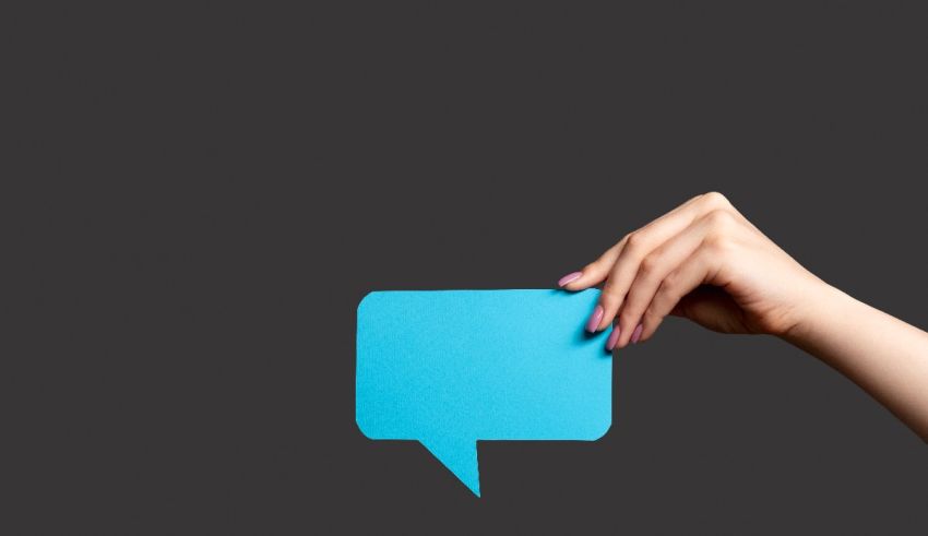 A woman's hand holding a blue speech bubble on a black background.