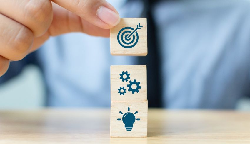 A businessman is holding wooden blocks with business icons on them.