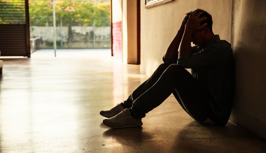 A man sitting on the floor with his head down.