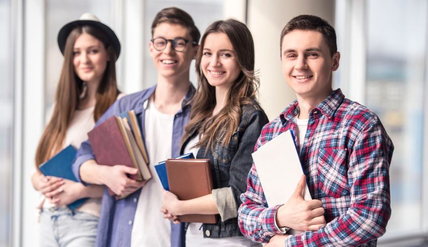 A group of students holding books in front of a window.