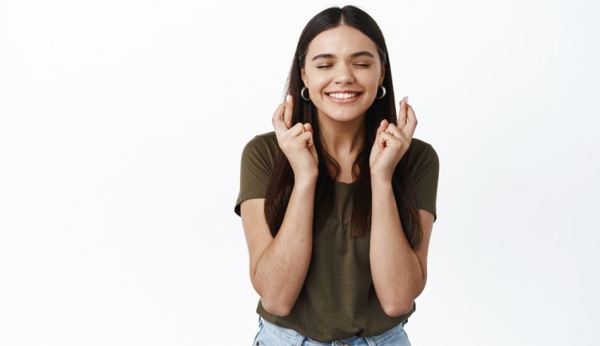 A smiling young woman with her hands on her ears.