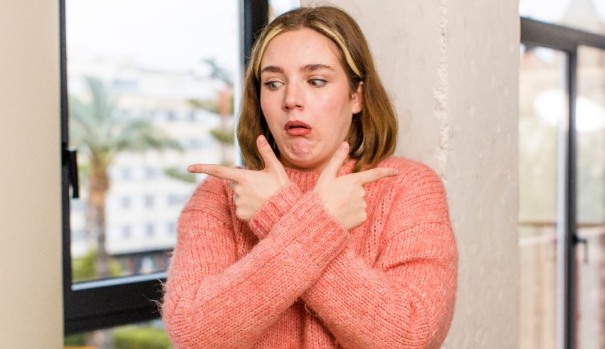 A woman in a pink sweater pointing her finger at the window.