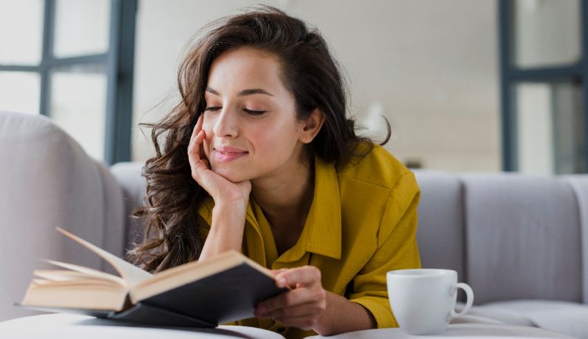 A young woman is reading a book on a couch.