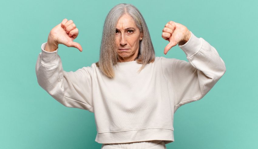 A woman showing her thumbs down on a blue background.