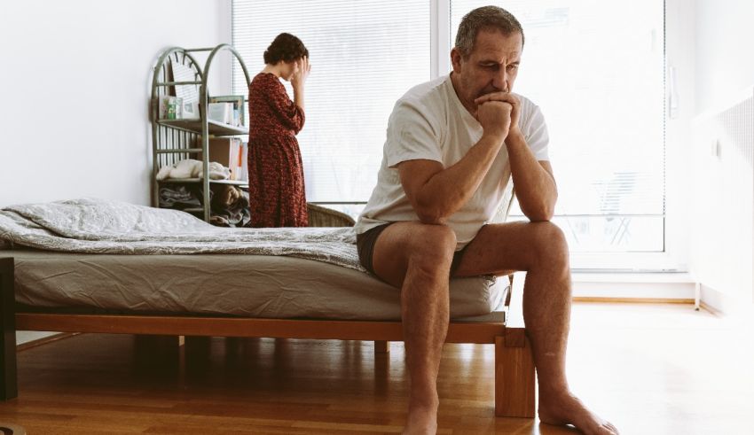 A man and woman sitting on a bed in a bedroom.