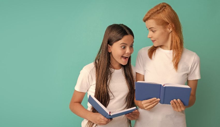 Two young girls are holding books in front of a turquoise background.