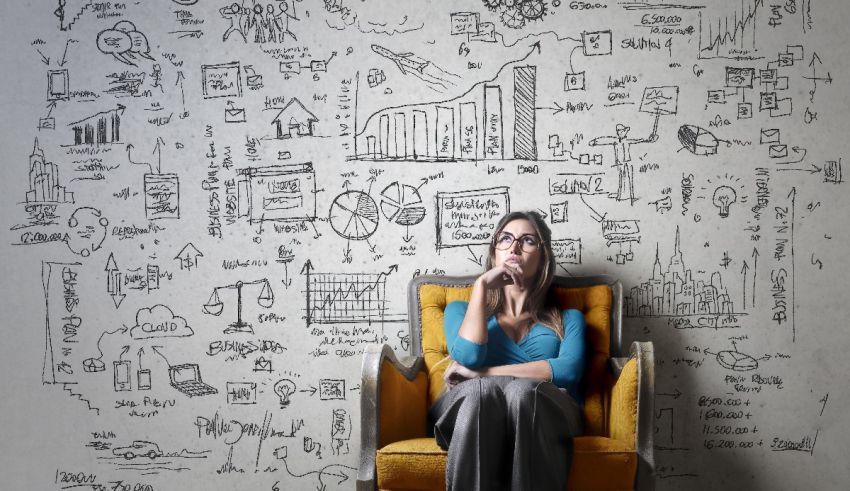 A woman sitting in a chair with doodles on the wall.